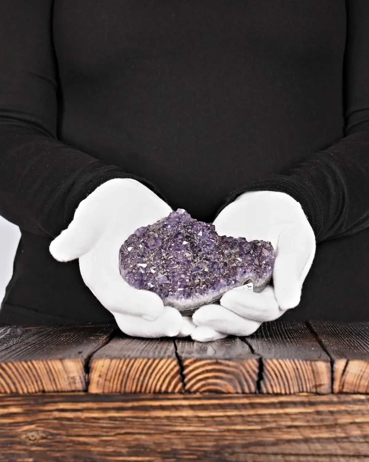 Das Amethyst-Herz mit der Berglandschaft in weiss behandschuhten Händen