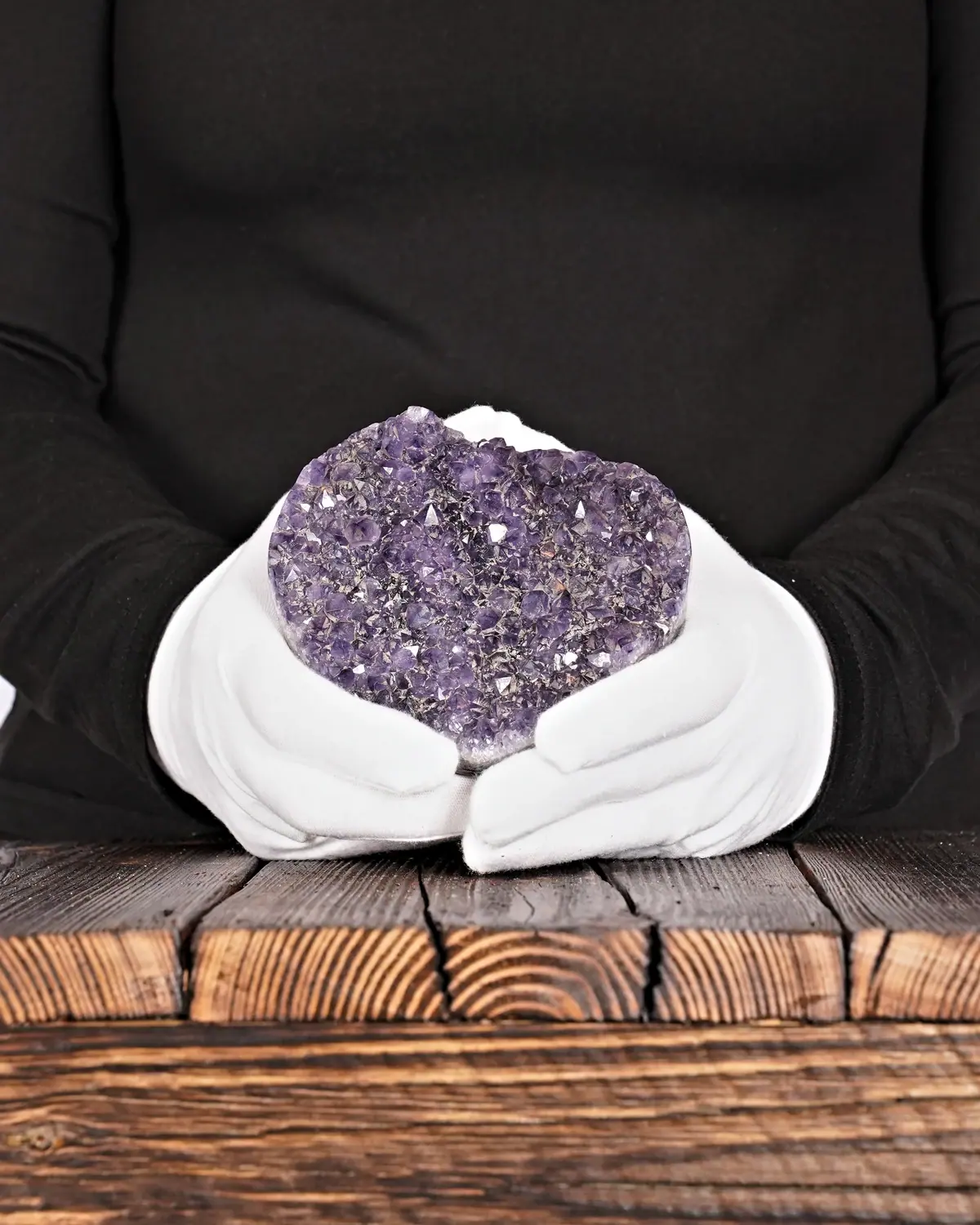 Das Amethyst-Herz mit der Berglandschaft in weiss behandschuhten Händen
