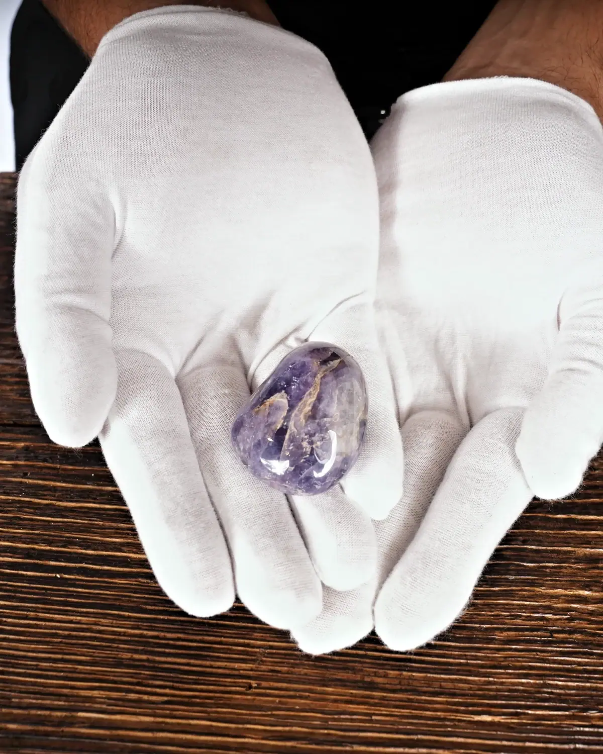 Handschmeichler aus Chevron-Amethyst in weiss behandschuhten Händen