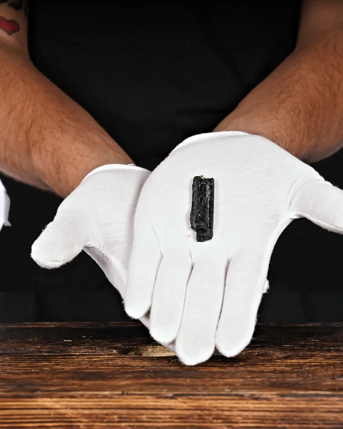 Die kleinen Turmalin-Schörl-Anhänger in weiss behandschuhten Händen