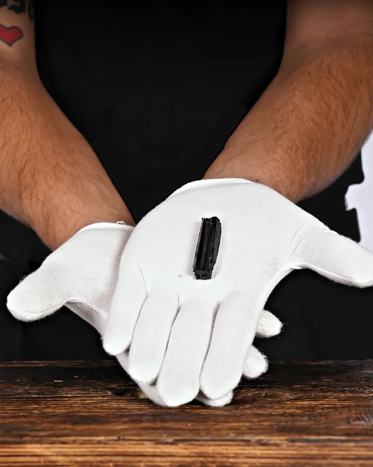 Die kleinen Turmalin-Schörl-Anhänger in weiss behandschuhten Händen