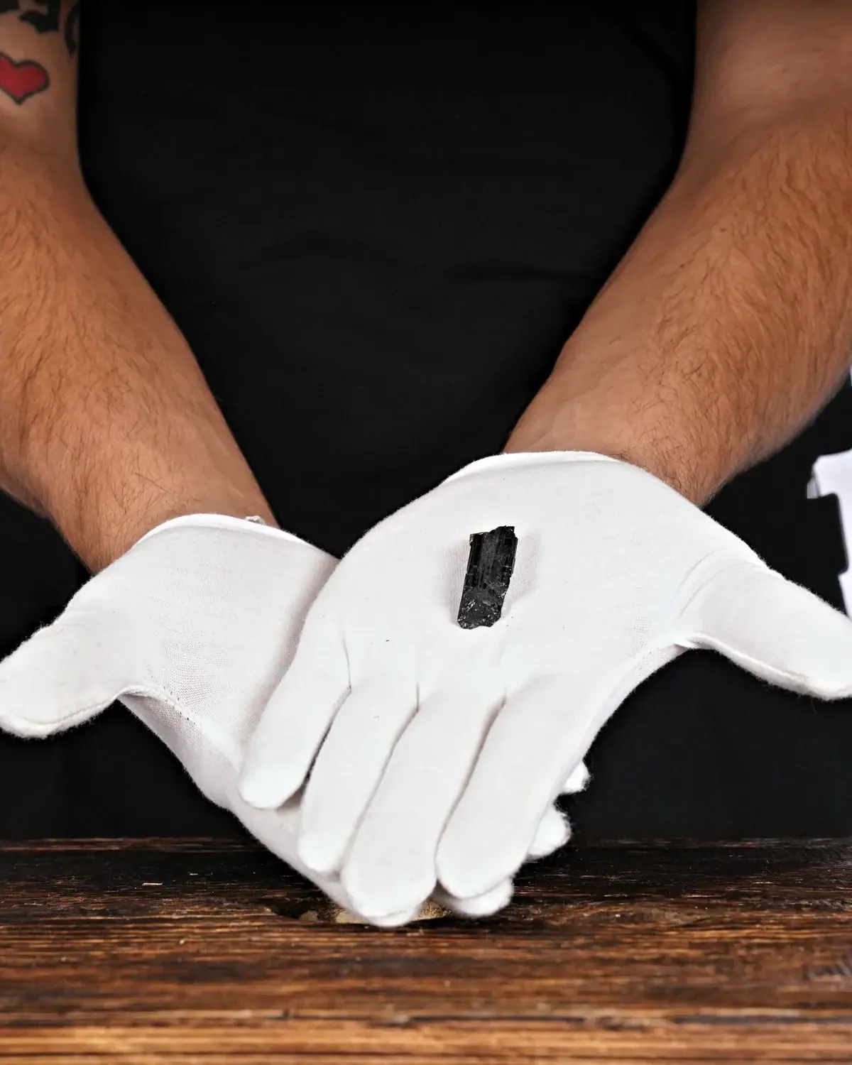 Die kleinen Turmalin-Schörl-Anhänger in weiss behandschuhten Händen