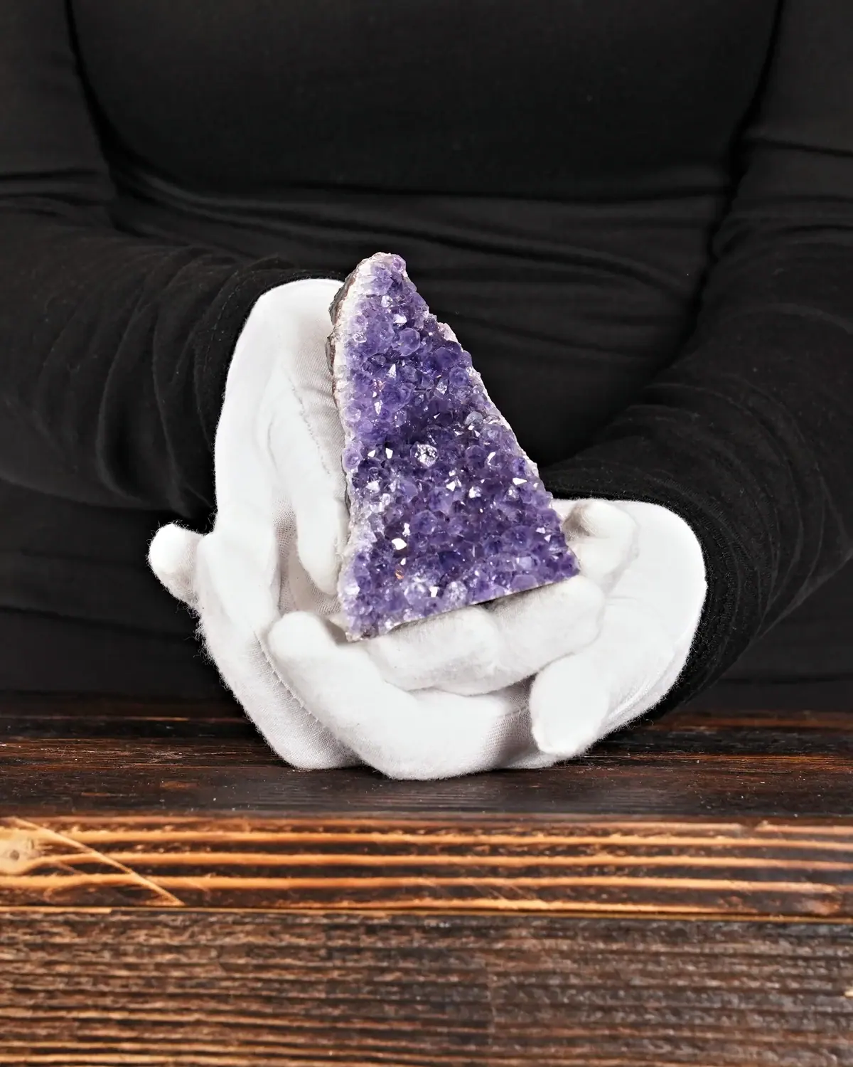 Der gebogene Amethyst-Fels in weiss behandschuhten Händen