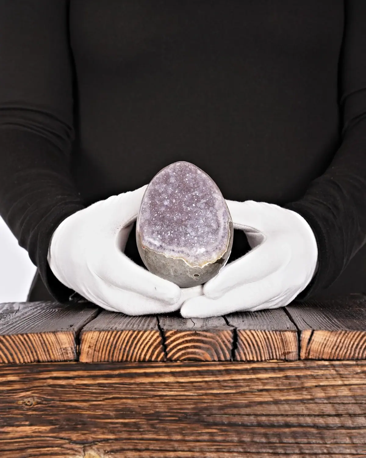 Das Amethyst-Ei in weiss behandschuhten Händen