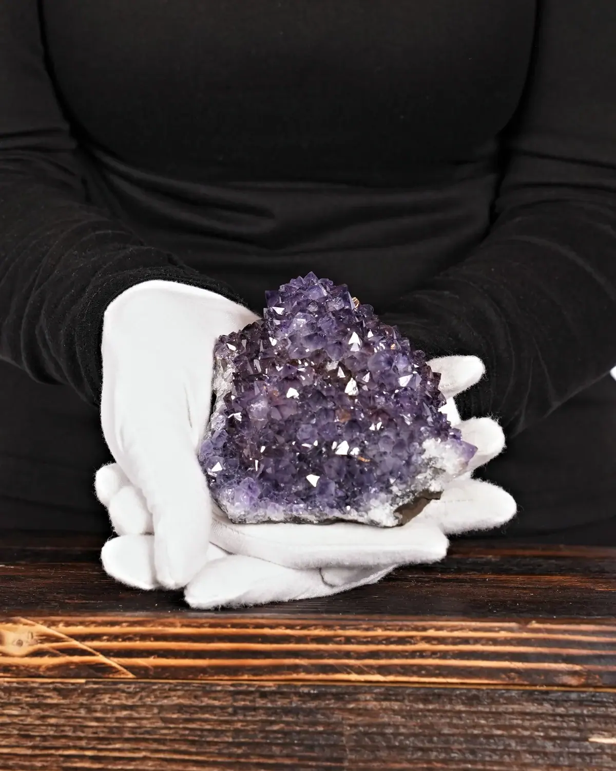 Der stachelige Amethyst-Igel in weiss behandschuhten Händen