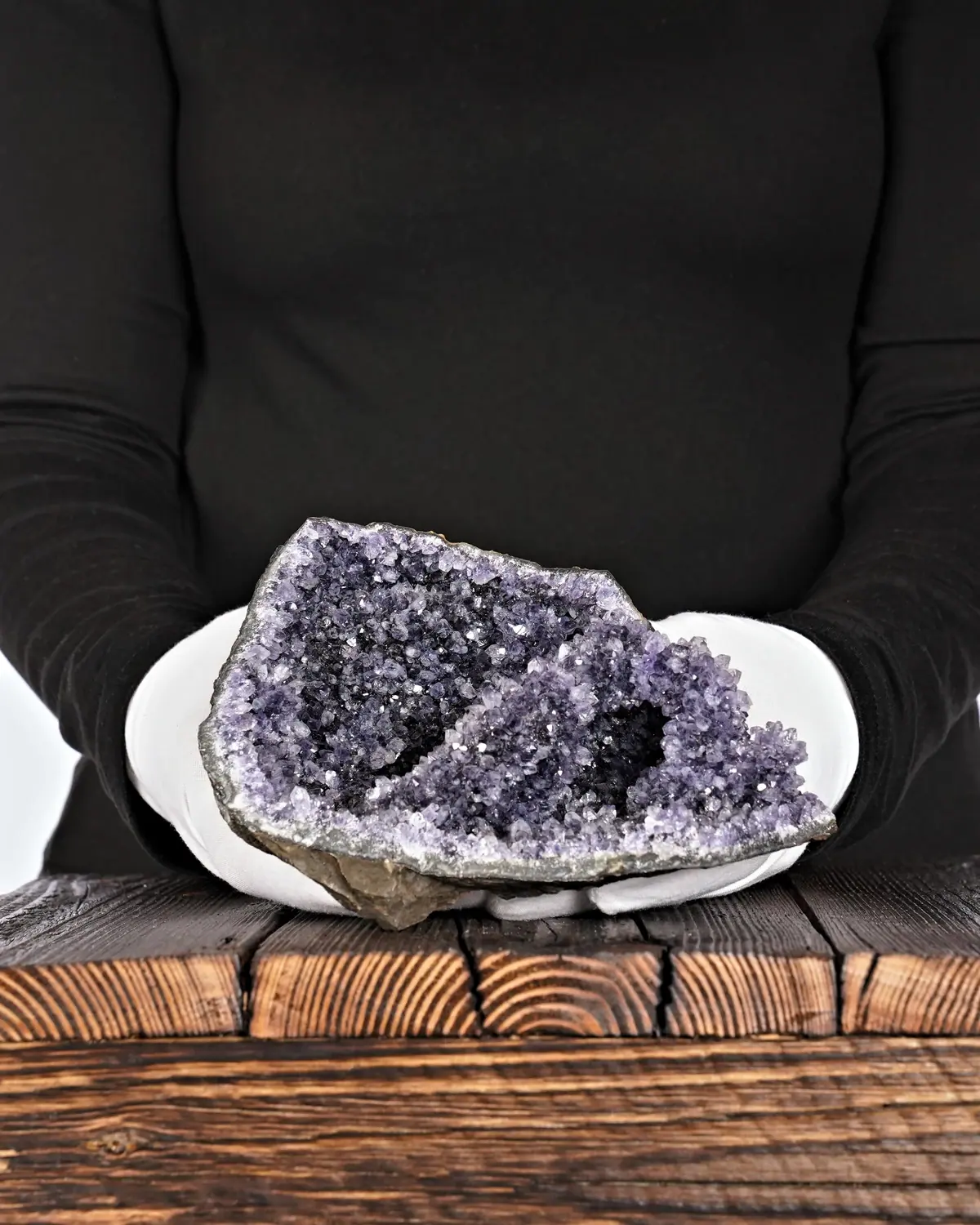 Die Höhle der violetten Kaktusamethyste in weiss behandschuhten Händen