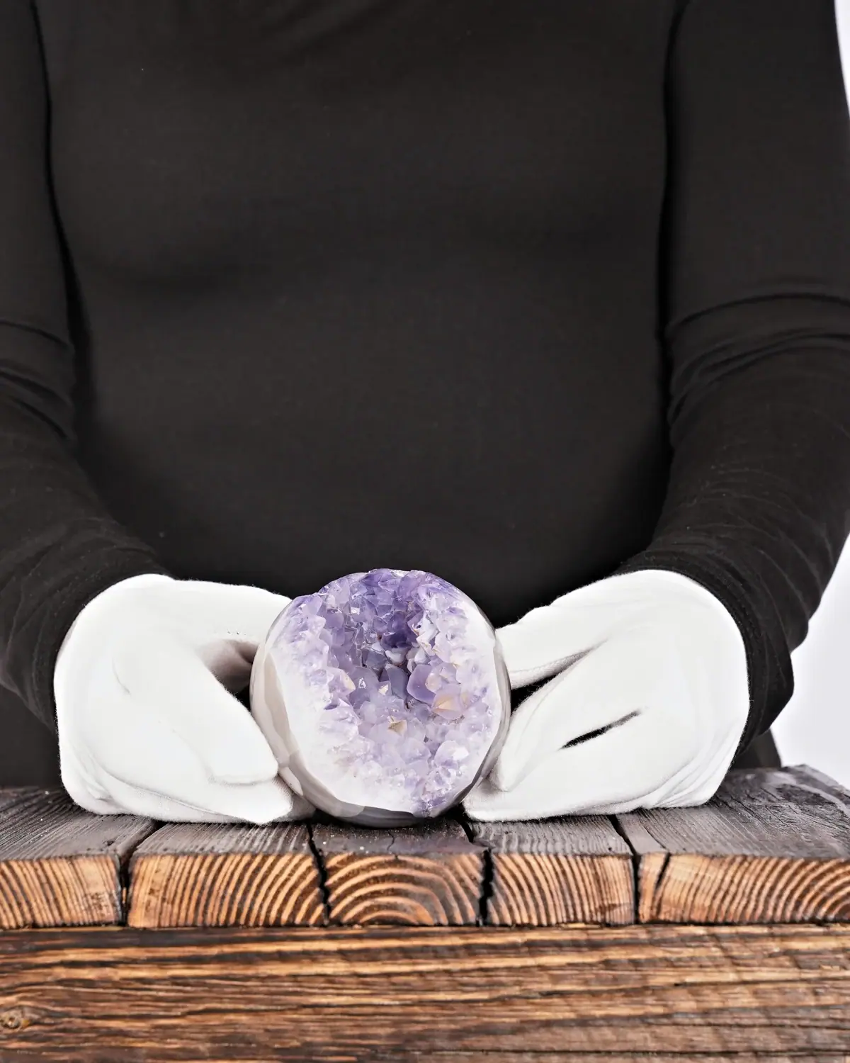 Amethyst-Halbkugel mit Druse und Bänderachat in weiss behandschuhten Händen