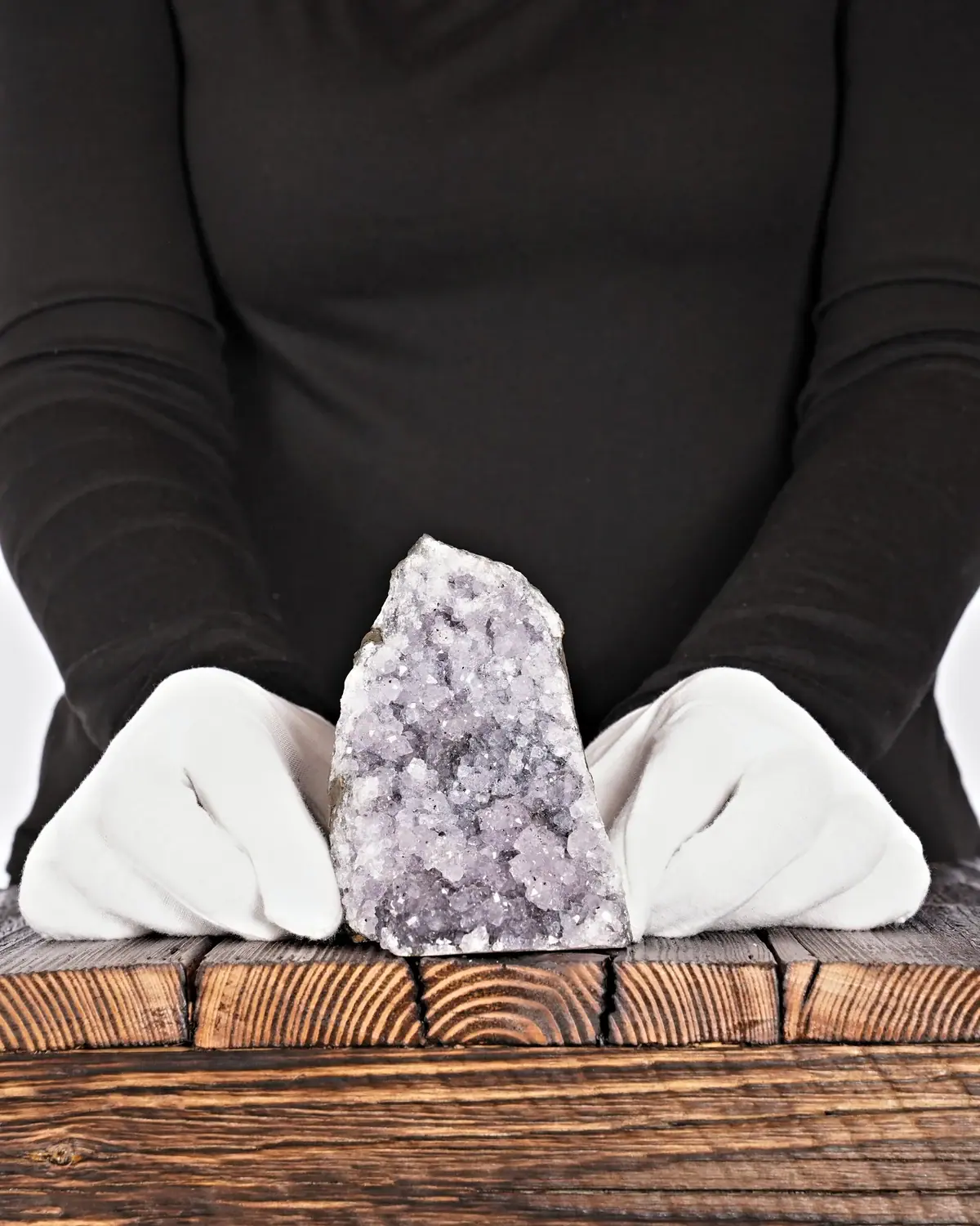 Der Felsen mit dem klaren lila Kaktusamethyst in weiss behandschuhten Händen
