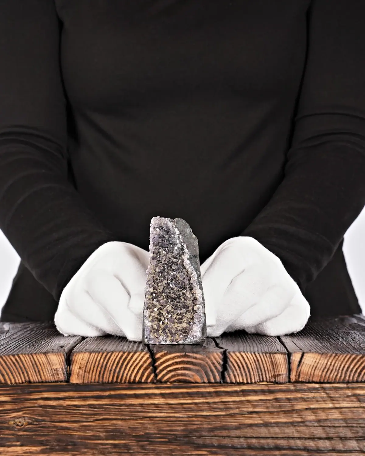Das verborgene Lila hinter dem grauen Amethyst in weiss behandschuhten Händen