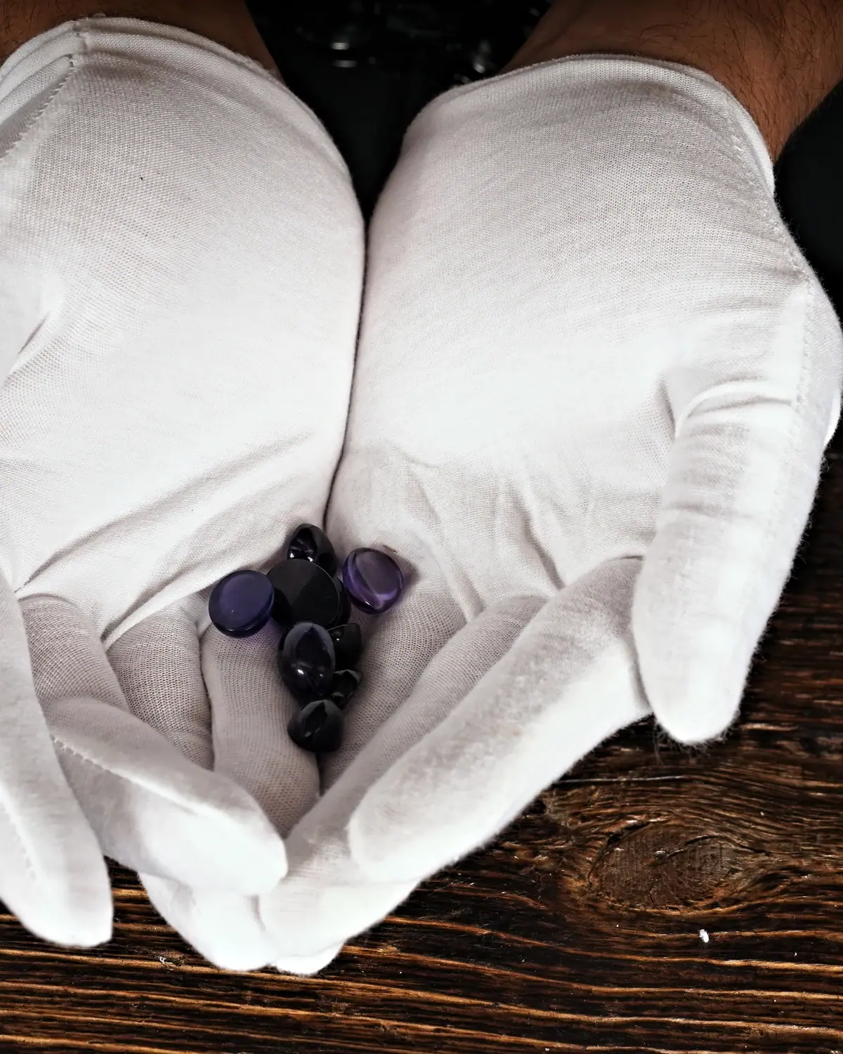 Amethyst-Cabochon in weiss behandschuhten Händen