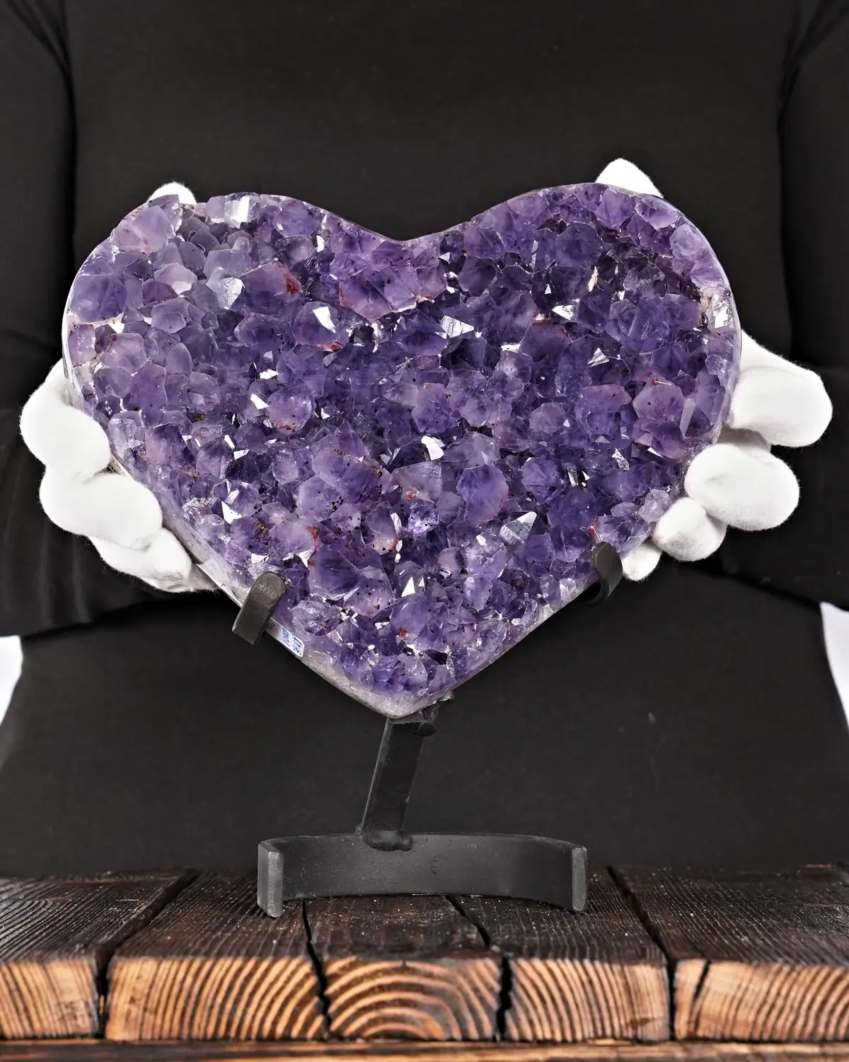 Geschwungenes Amethyst-Herz aus Brasilien in weiss behandschuhten Händen