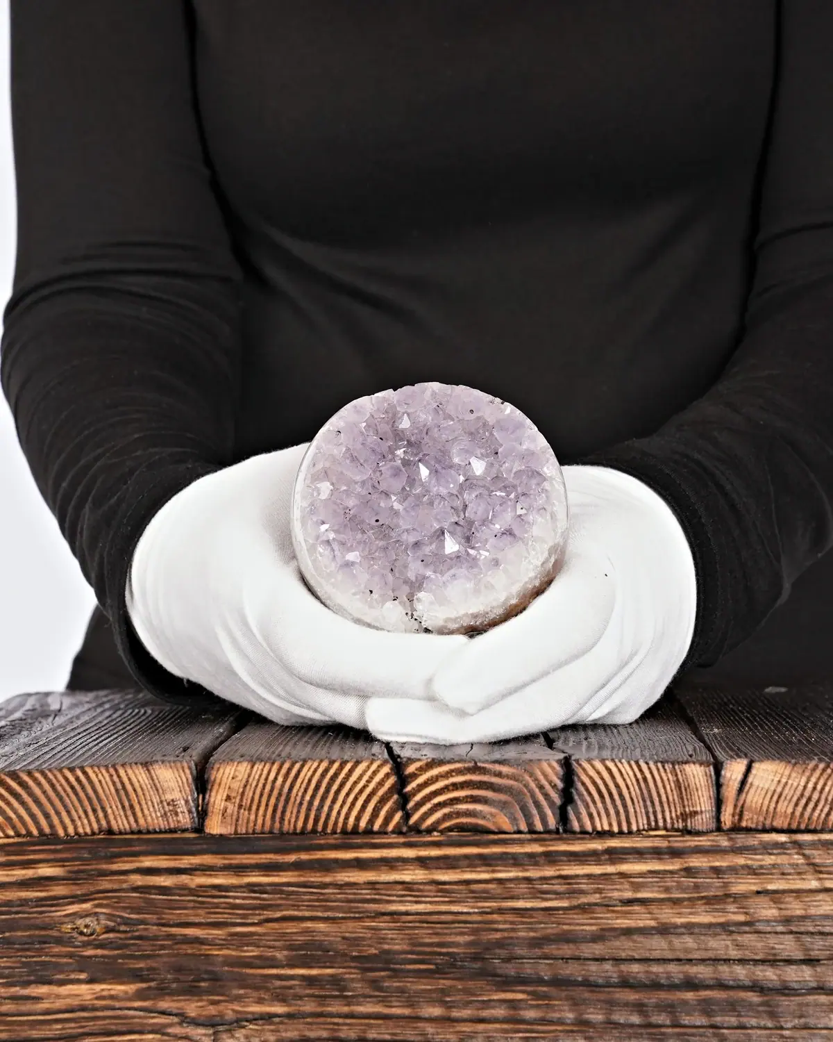 Amethyst Kugel Nr. 129 in weiss behandschuhten Händen