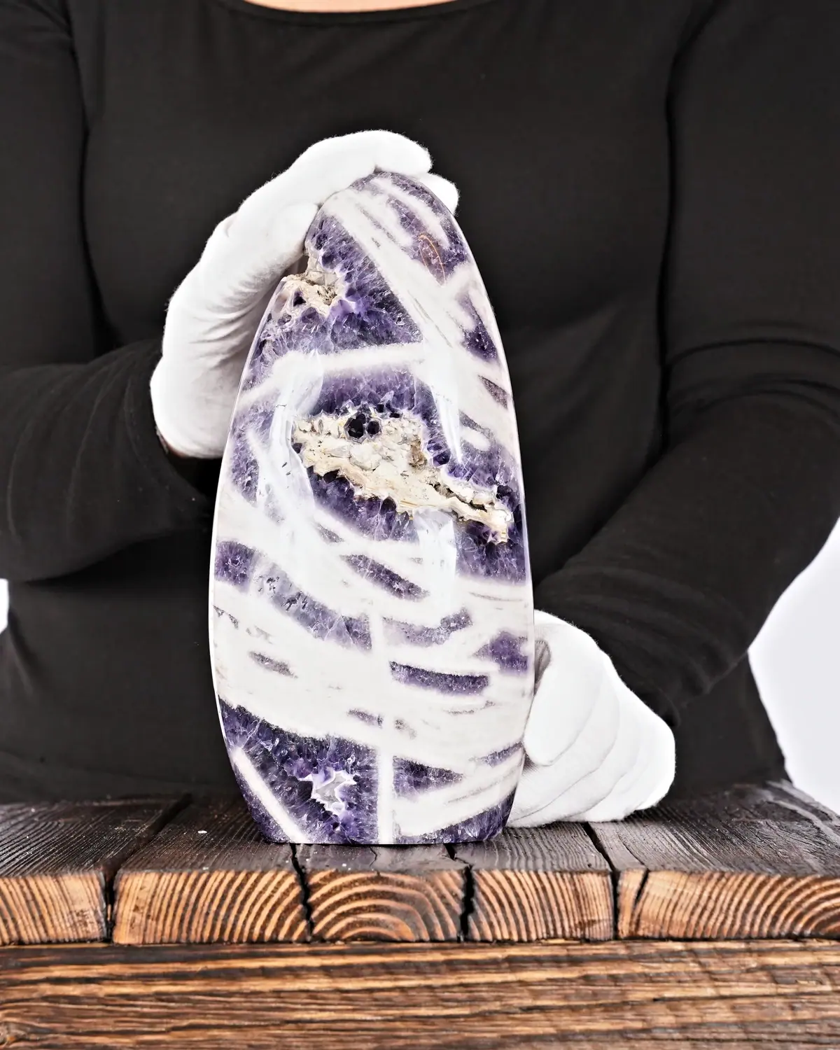 Der Chevron Amethyst Fels in weiss behandschuhten Händen