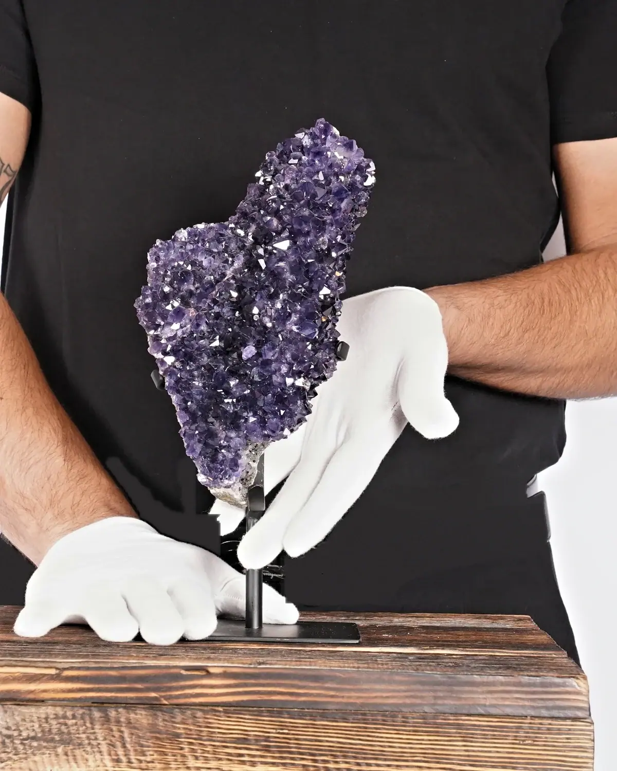 Der lange Kaktus-Amethyst in weiss behandschuhten Händen
