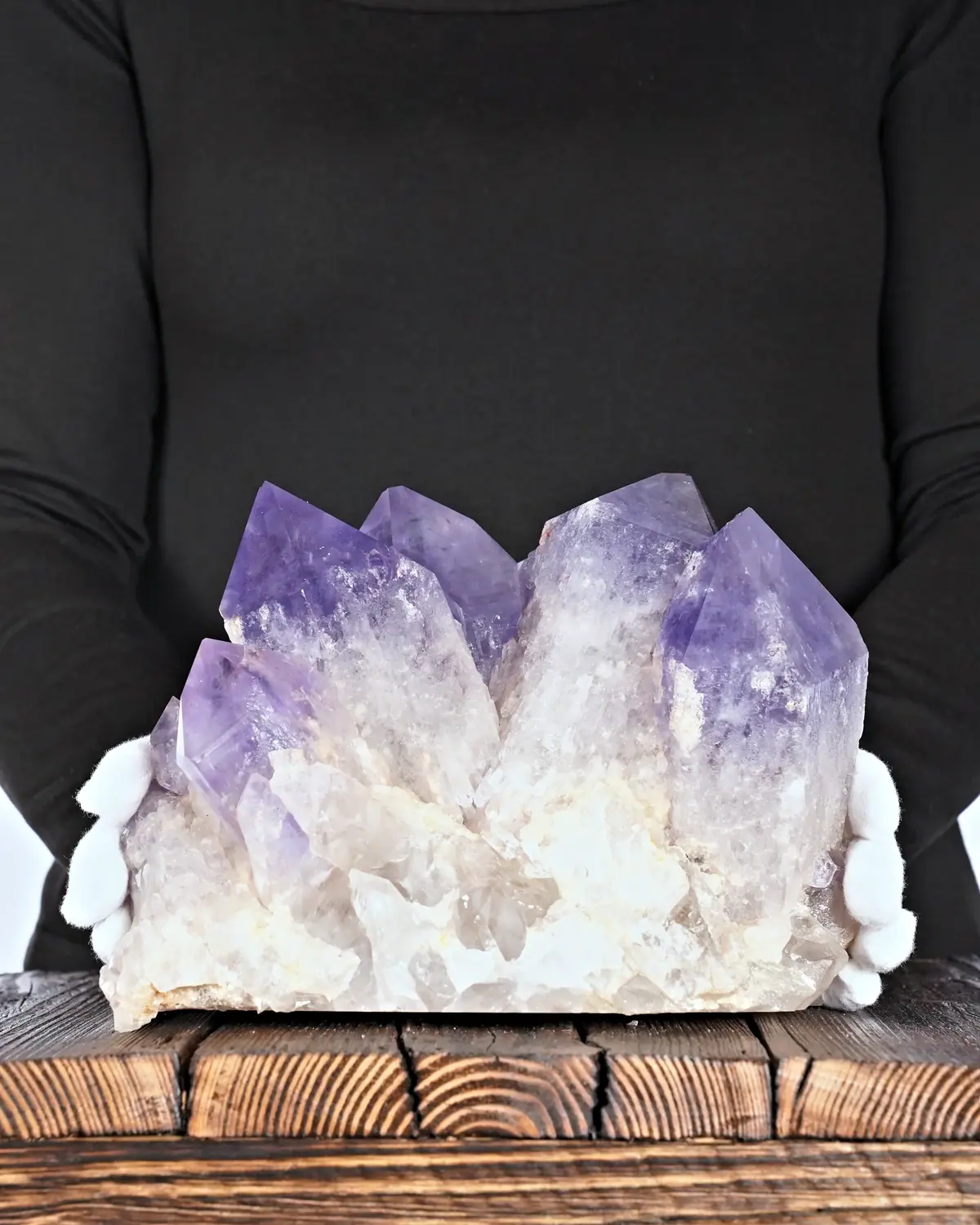Die fünf Kristallspitzen (Amethystgruppe aus Bolivien) in weiss behandschuhten Händen