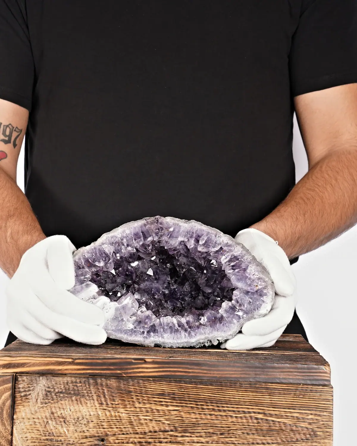 Die lila Amethyst-Geode mit Regenbogenschimmer in weiss behandschuhten Händen