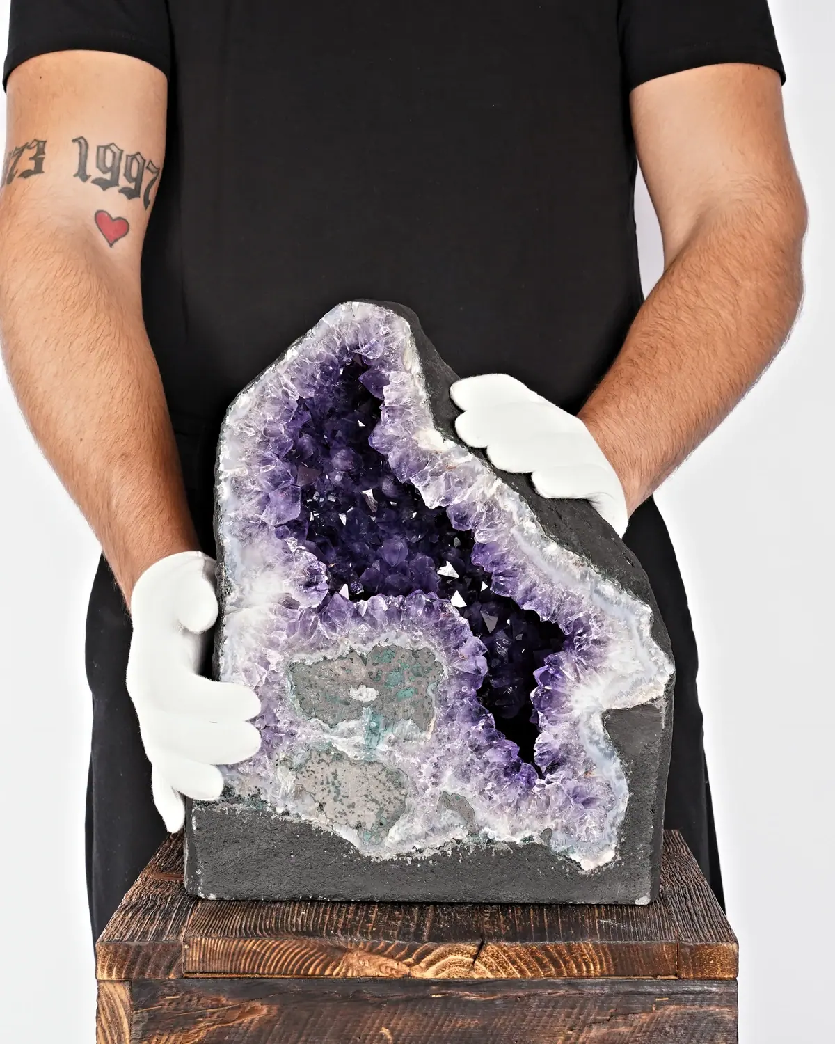 Die aufleuchtende Amethyst-Druse in weiss behandschuhten Händen
