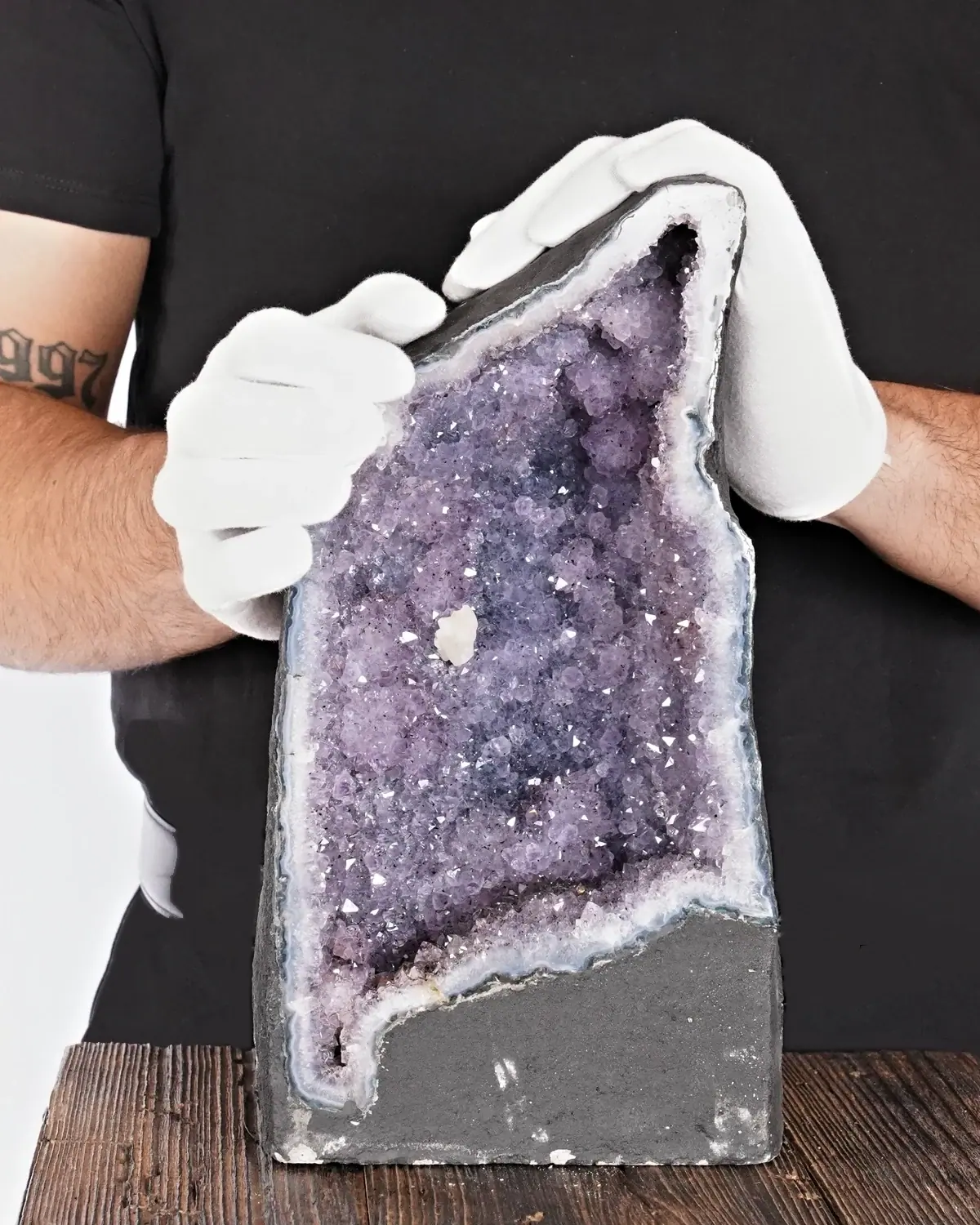 Die Pinguin-Amethyst-Druse in weiss behandschuhten Händen