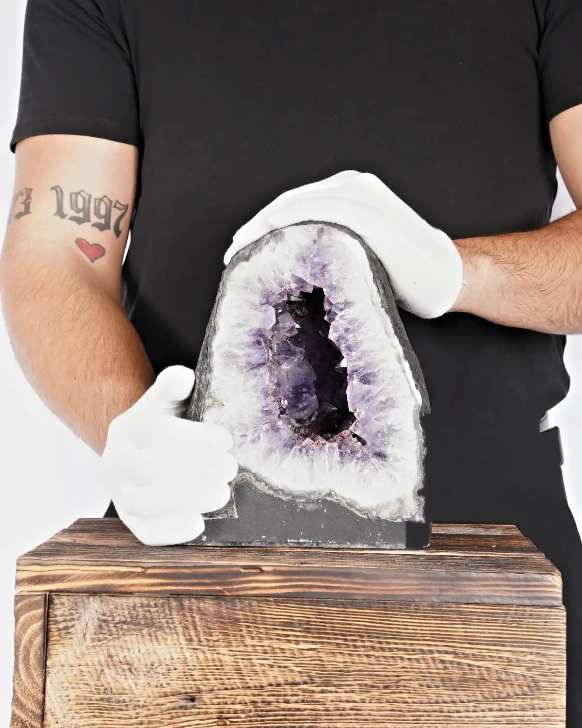Die Gold-Nuggets-Amethyst-Druse in weiss behandschuhten Händen