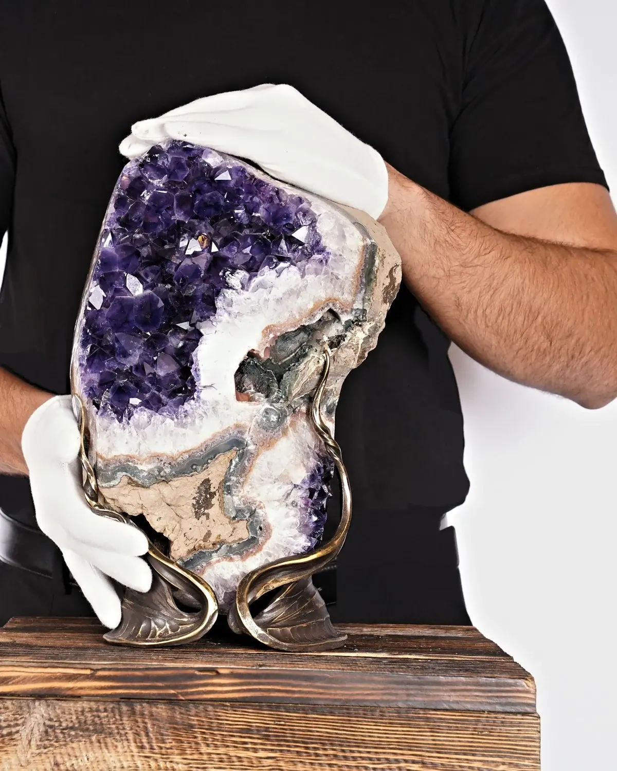 Die leuchtende Amethyst-Skulptur in weiss behandschuhten Händen