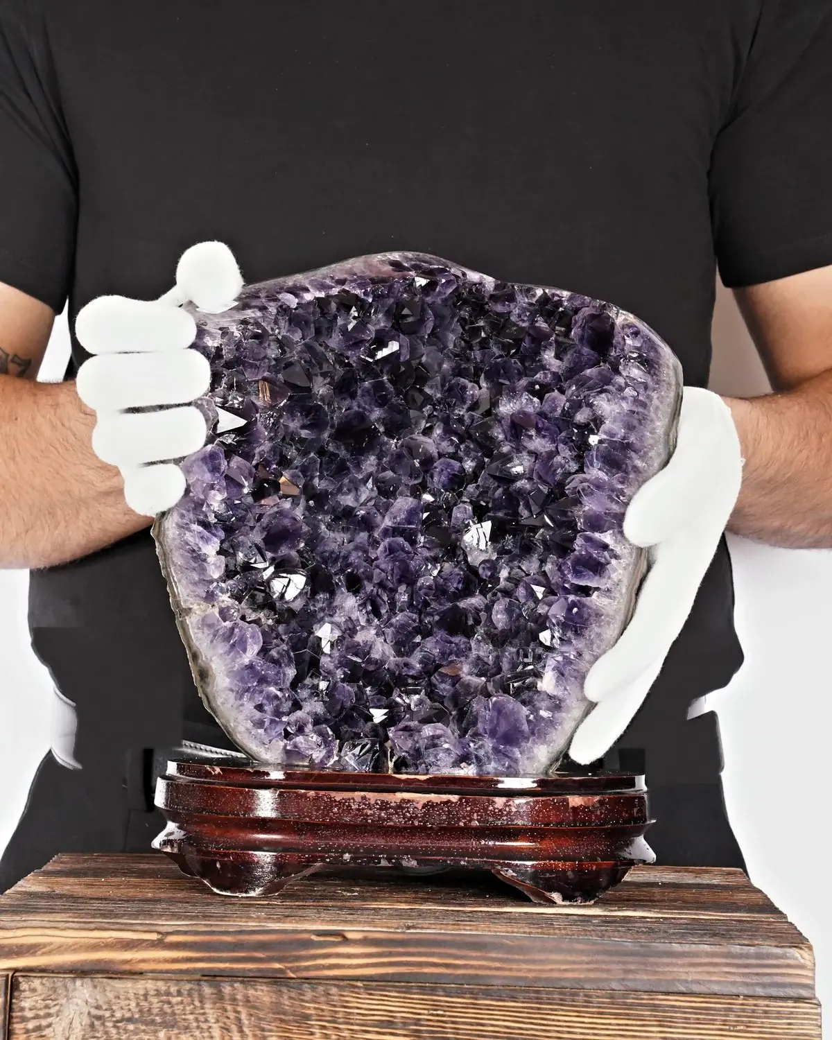 Die schwungvolle Amethyst-Skulptur in weiss behandschuhten Händen