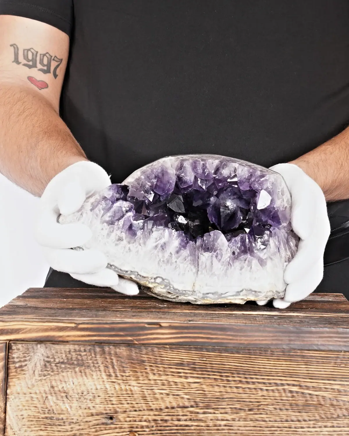 Die kräftigende Amethyst-Geode in weiss behandschuhten Händen