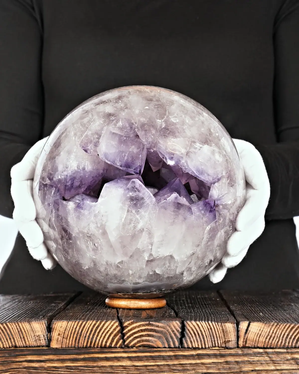 Amethyst-Kugel mit gegenüberstehenden grossen Kristallen in weiss behandschuhten Händen