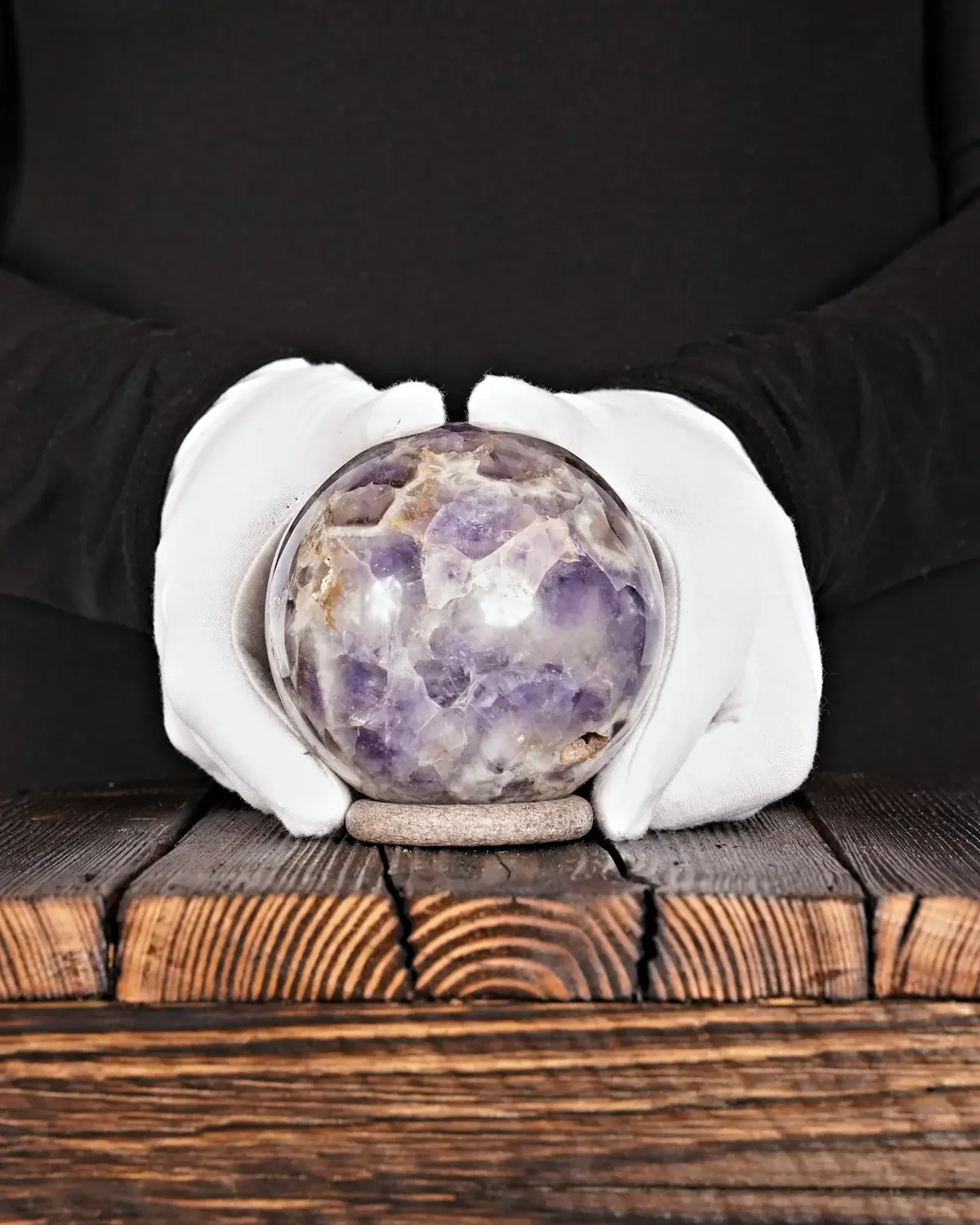 Amethyst Kugel Nr. 171 in weiss behandschuhten Händen