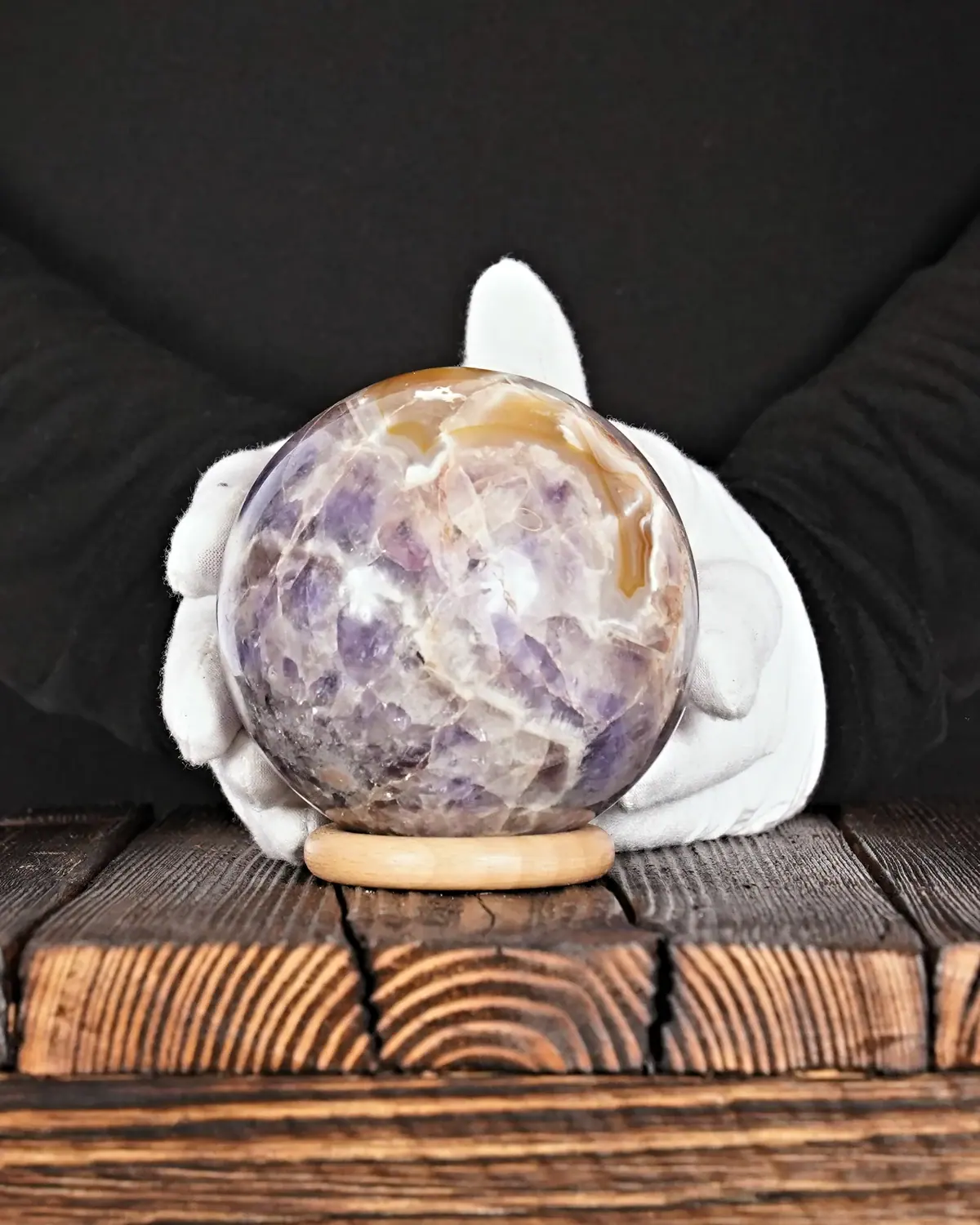 Das Entenküken in der Chevron-Amethyst-Kugel in weiss behandschuhten Händen