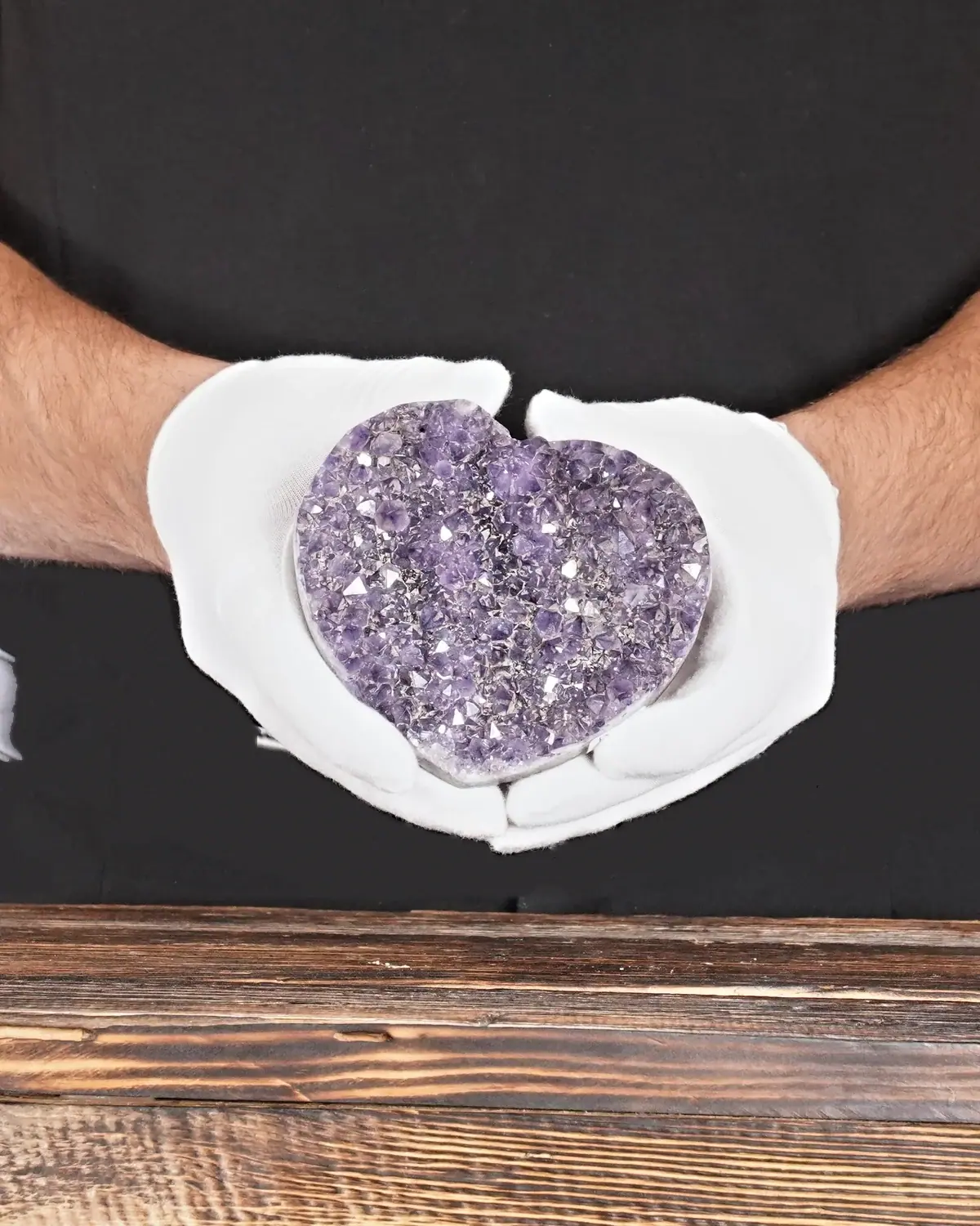 Das Amethyst-Herz mit der Berglandschaft in weiss behandschuhten Händen