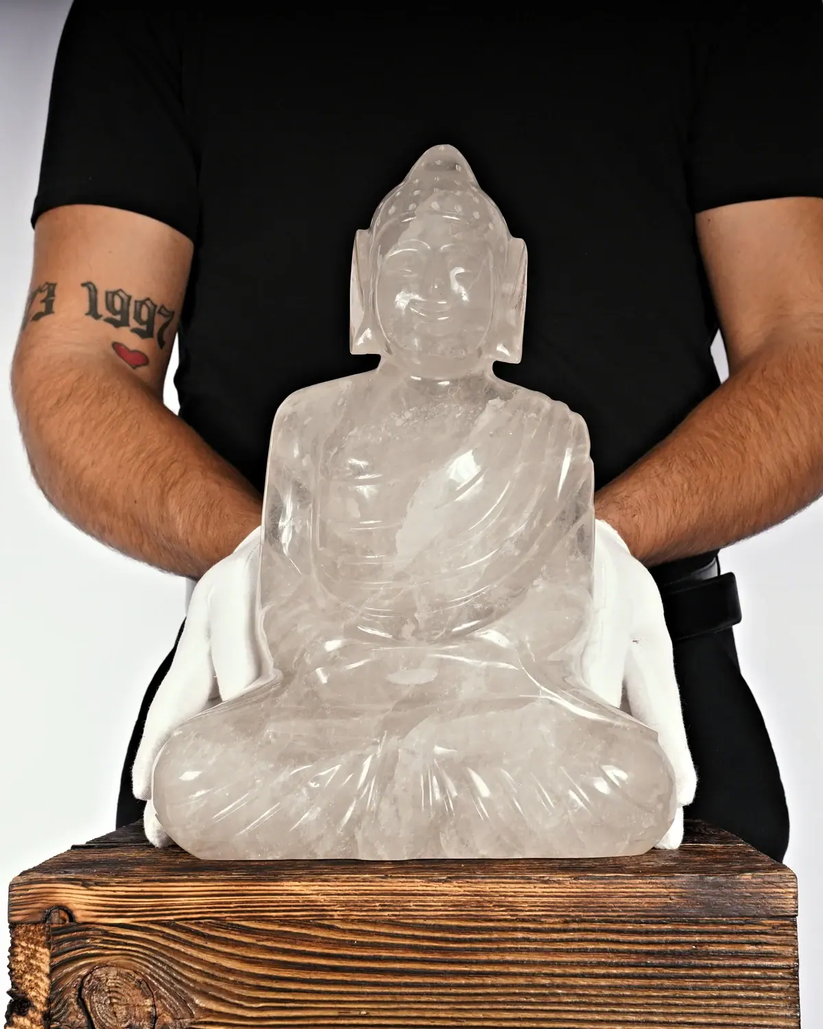 Bergkristall Buddha Nr. 61 in weiss behandschuhten Händen