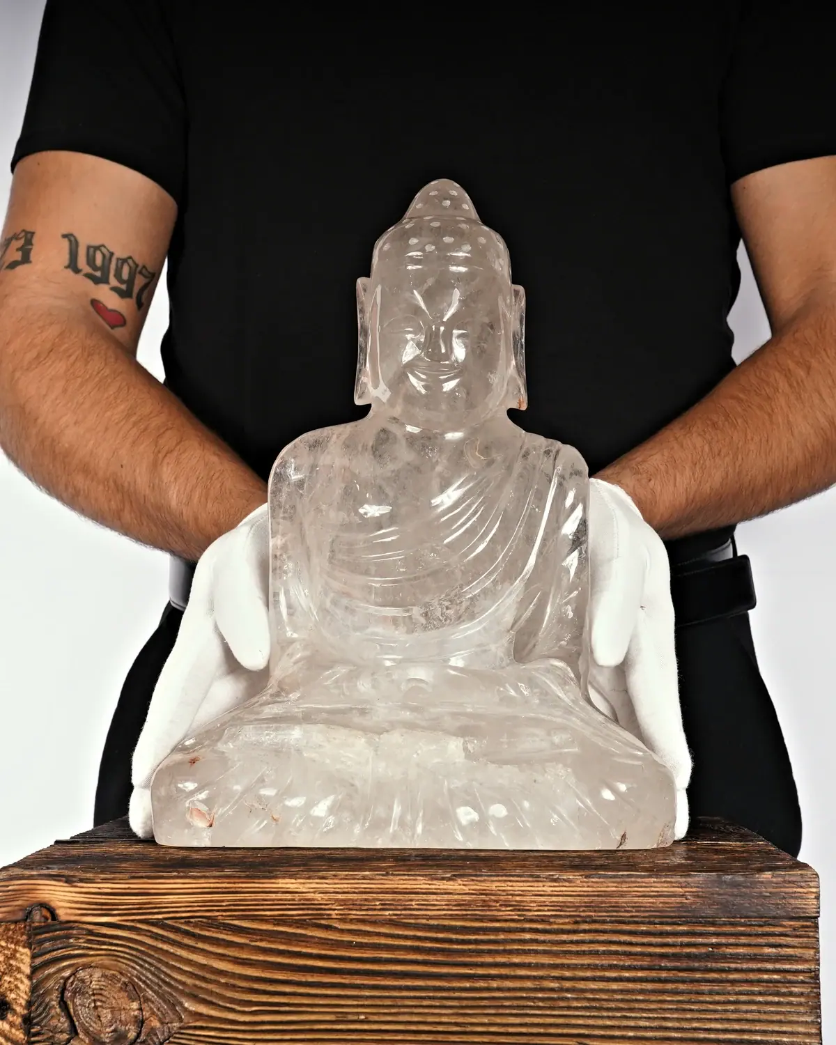 Bergkristall Buddha Nr. 63 in weiss behandschuhten Händen