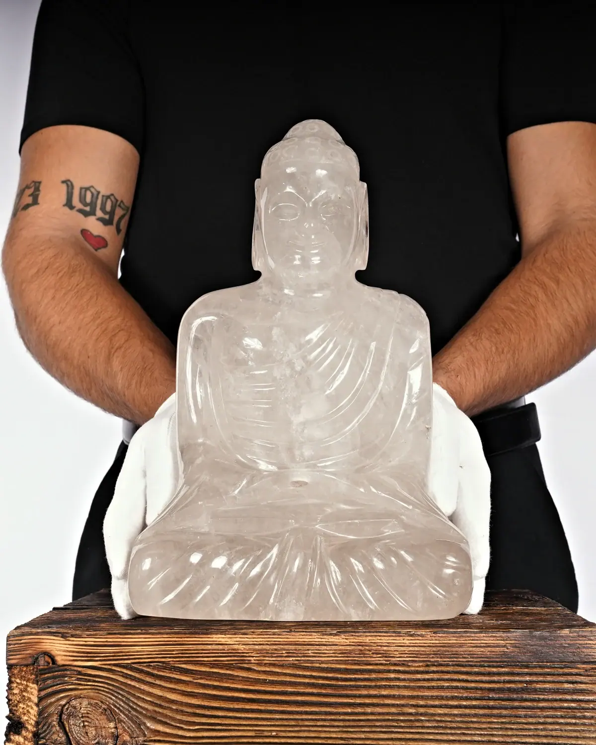 Bergkristall Buddha Nr. 64 in weiss behandschuhten Händen