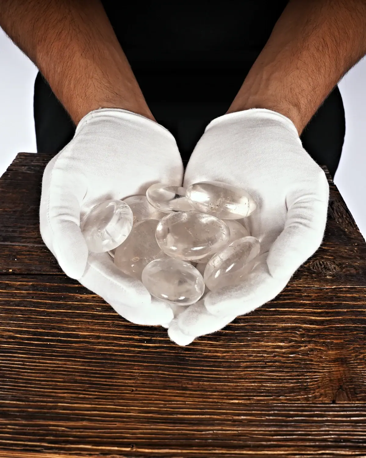 Handschmeichler aus klarem Bergkristall in weiss behandschuhten Händen