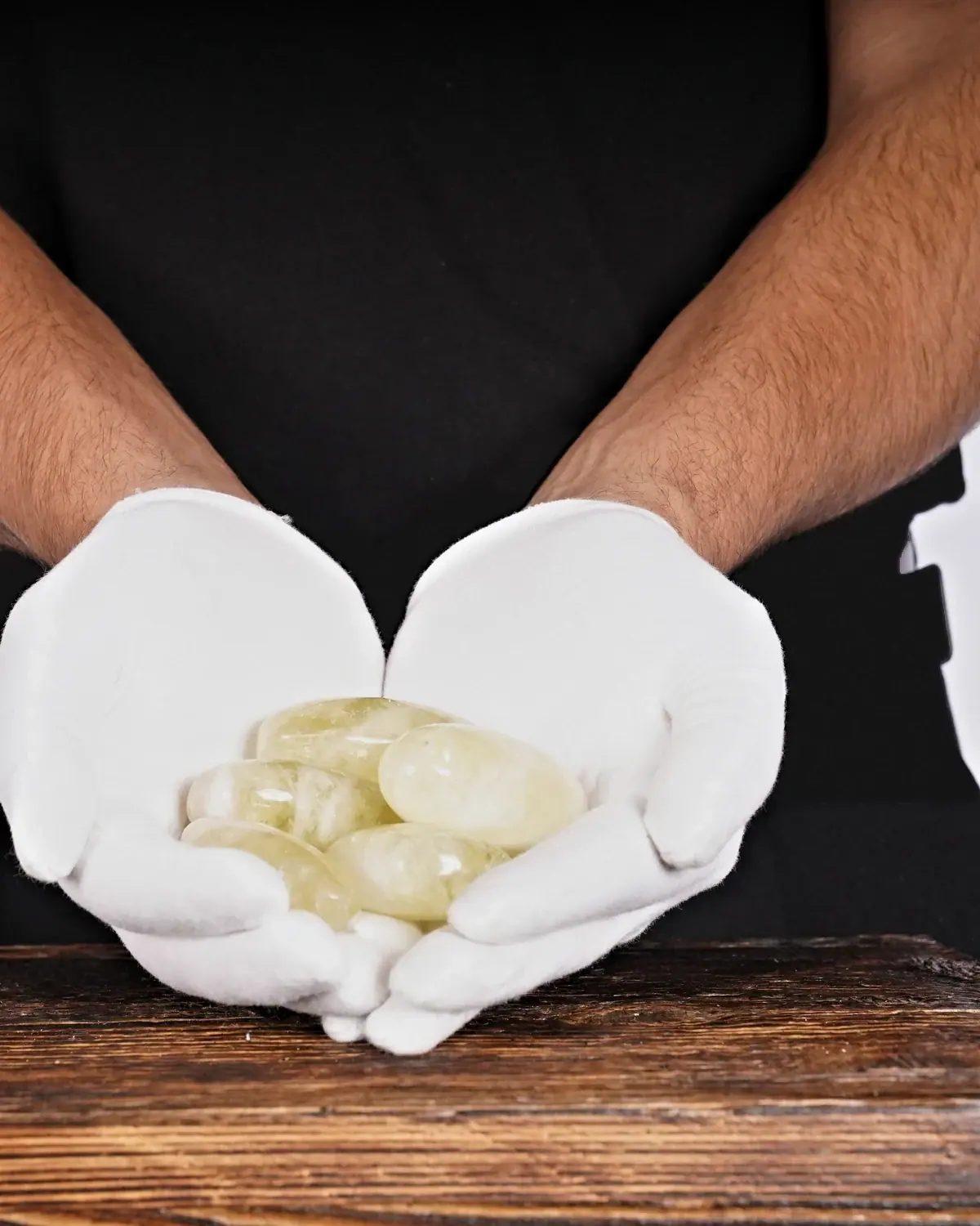 Citrin Trommelsteine Nr. 25 in weiss behandschuhten Händen