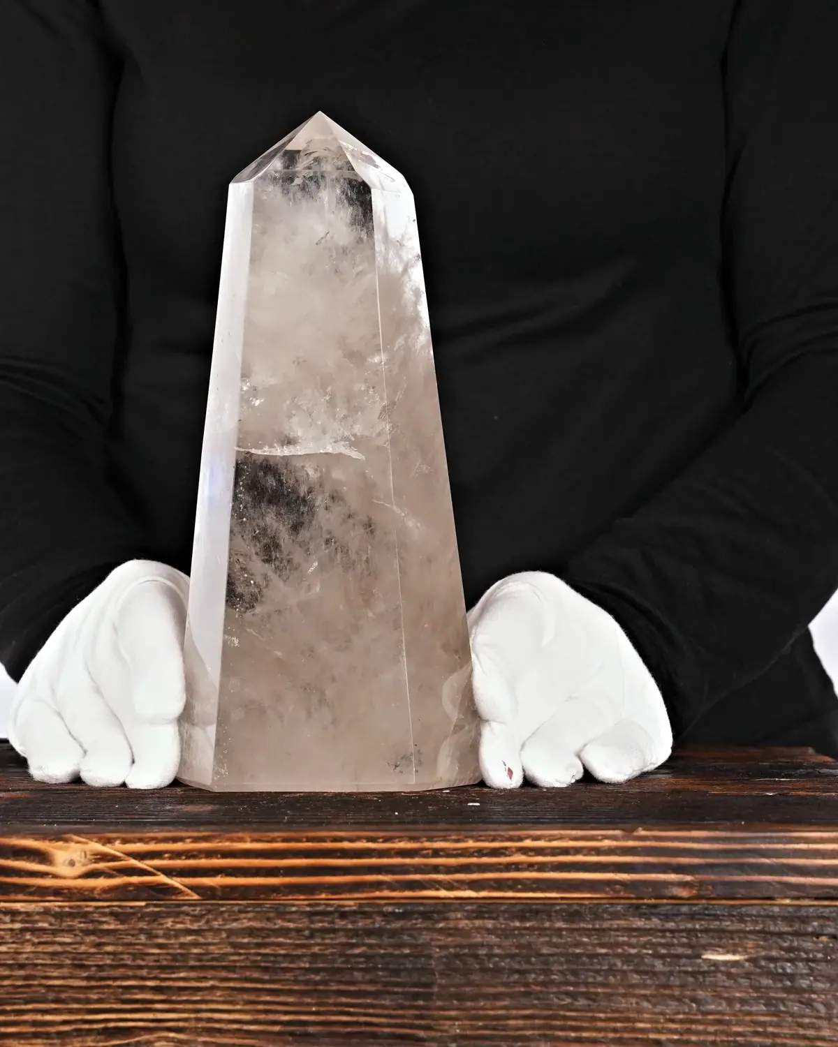 Die wolkige, stämmige Rauchquarzspitze mit Wolkenoptik in weiss behandschuhten Händen