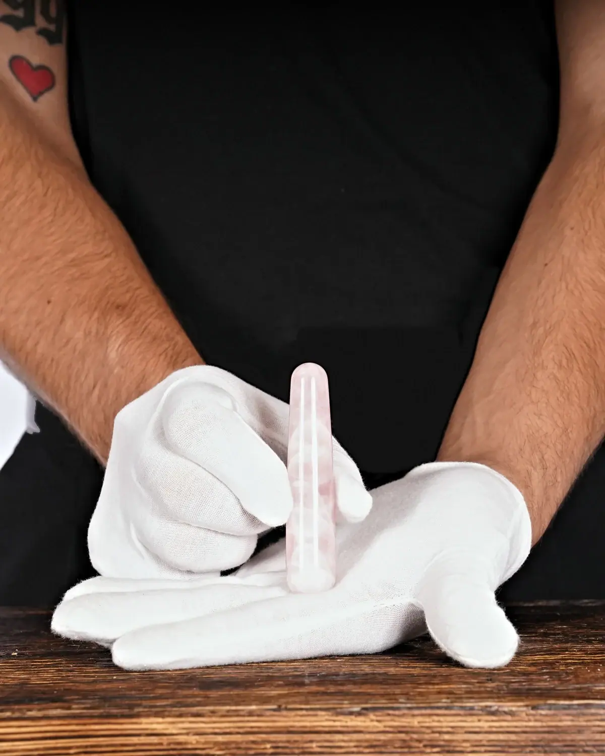 Rosenquarz-Massagestäbe in weiss behandschuhten Händen