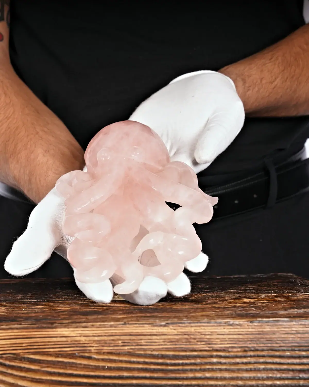 Rosenquarz Krake Nr. 19 in weiss behandschuhten Händen