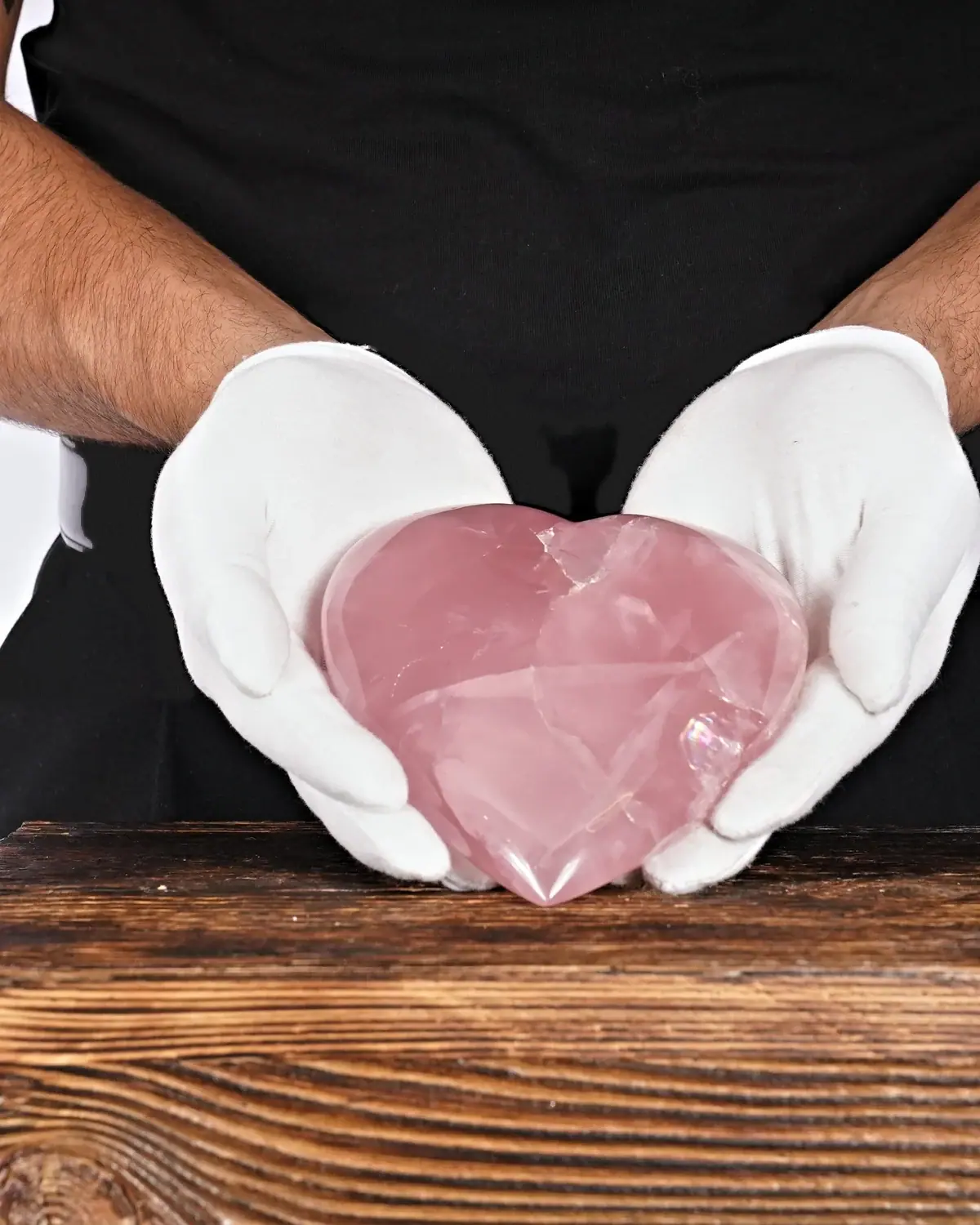 Das Rosenquarzherz der durchdringenden Liebe in weiss behandschuhten Händen