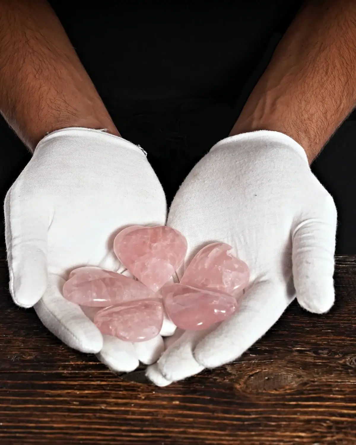 Die kleinen Rosenquarzherzen in weiss behandschuhten Händen