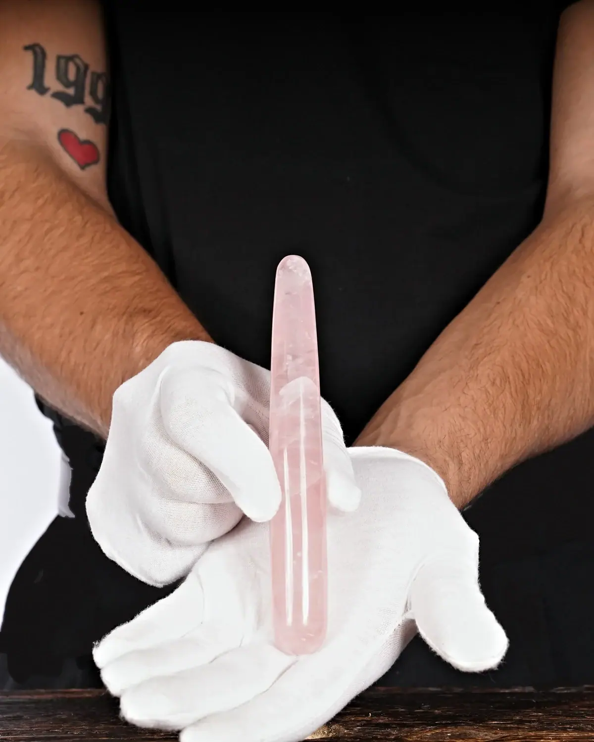 Rosenquarz Massagestäbe Nr. 33 in weiss behandschuhten Händen