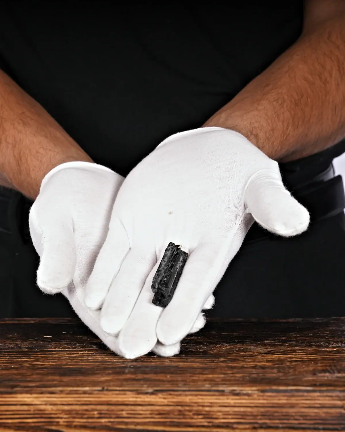Die kleinen Turmalin-Schörl-Anhänger in weiss behandschuhten Händen